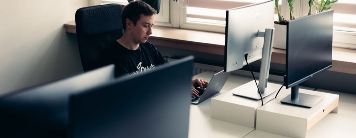 Engineer building MedTech software at a multi-monitor desk